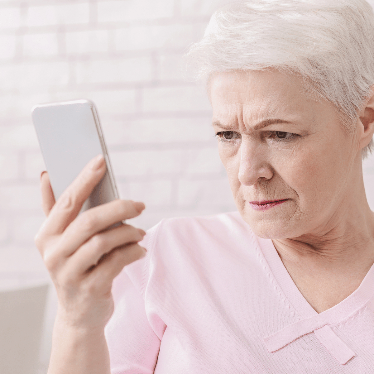 Verschwommen sehen beim Blick auf das Smartphone Ältere Frau blickt konzentriert auf ihr Smartphone und versucht aufgrund von verschwommenem Sehen den Bildschirm zu erkennen.